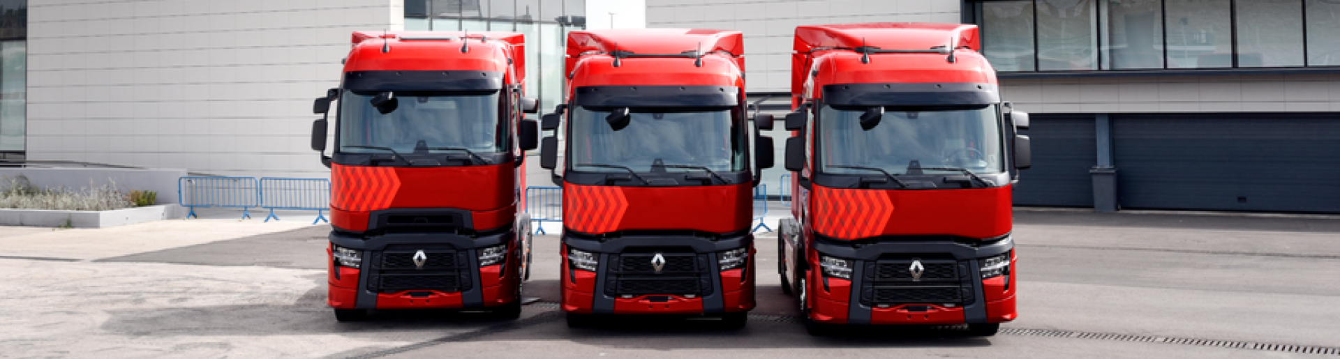 Vista frontal de tres camiones RENAULT TRUCKS T color rojo para larga distancia aparcados en batería