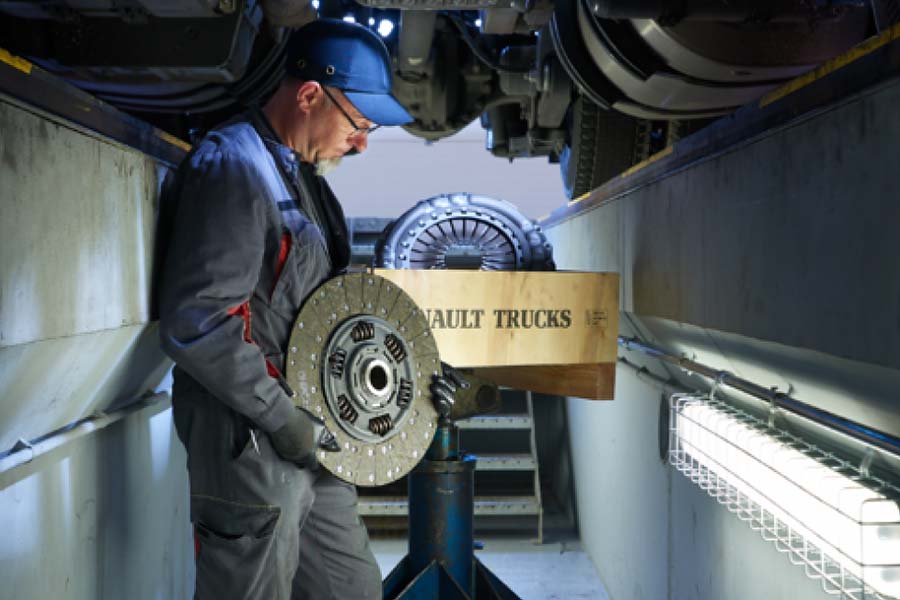 Mecánico en taller RENAULT TRUCKS sosteniendo recambio de camión